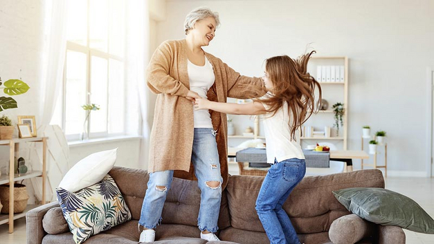 Eine lange Wohndauer, geerbtes Wohneigentum aus Familienbesitz und Kinder beispielsweise sorgen für Erinnerungen im Zusammenhang mit dem Eigenheim und steigern den emotionalen Wert der Immobilie. Eine Frau mit einem Mädchen auf dem Sofa.